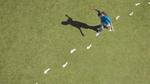A woman walks on white footprints across a grassy field