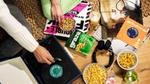 Graze snacks, a pair of headphones and a vinyl record player are placed on a wooden floor.