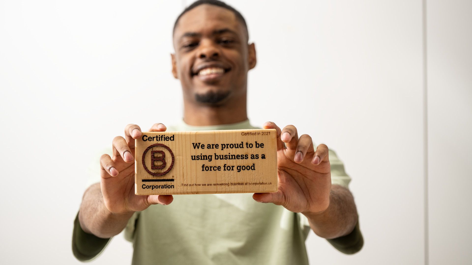 A man holding a small plank that says "Certified B Corporation".