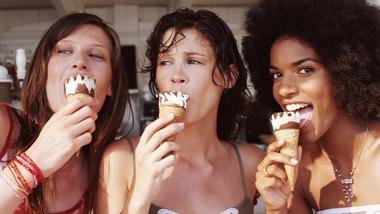 Three women stand together enjoying Cornetto ice cream cones.
