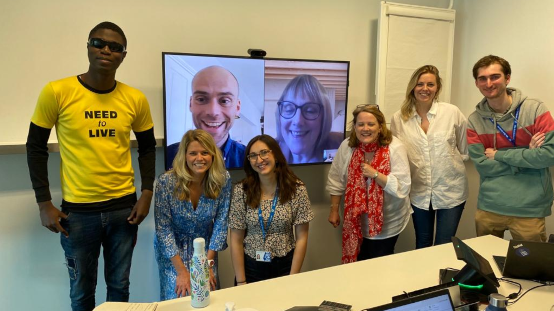Ademola standing in a meeting room with his team