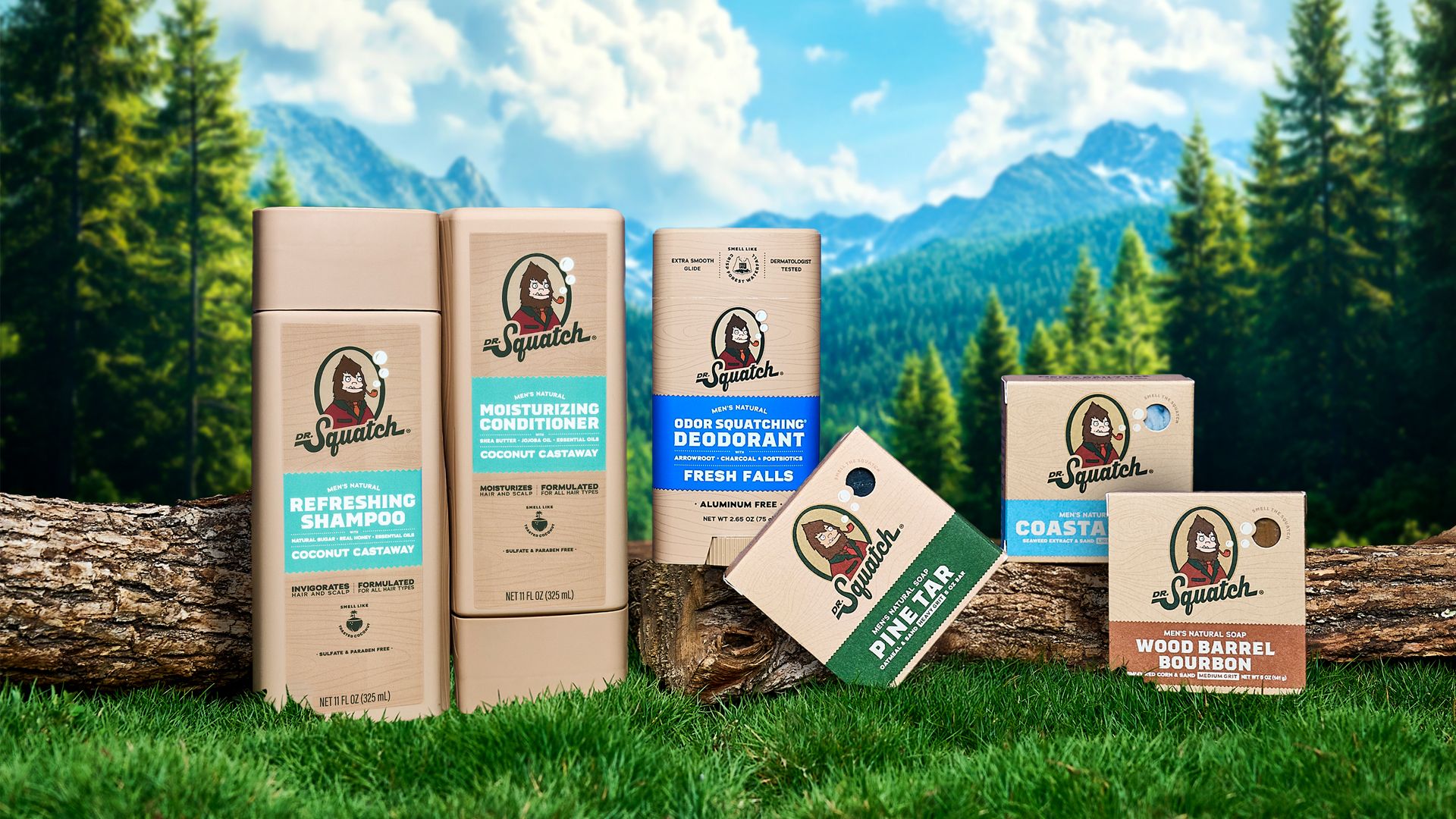 Dr. Squatch grooming products – including shampoo, conditioner, deodorant, and soaps – arranged on logs and grass in a natural outdoor setting with trees, mountains, and a blue sky in the background.