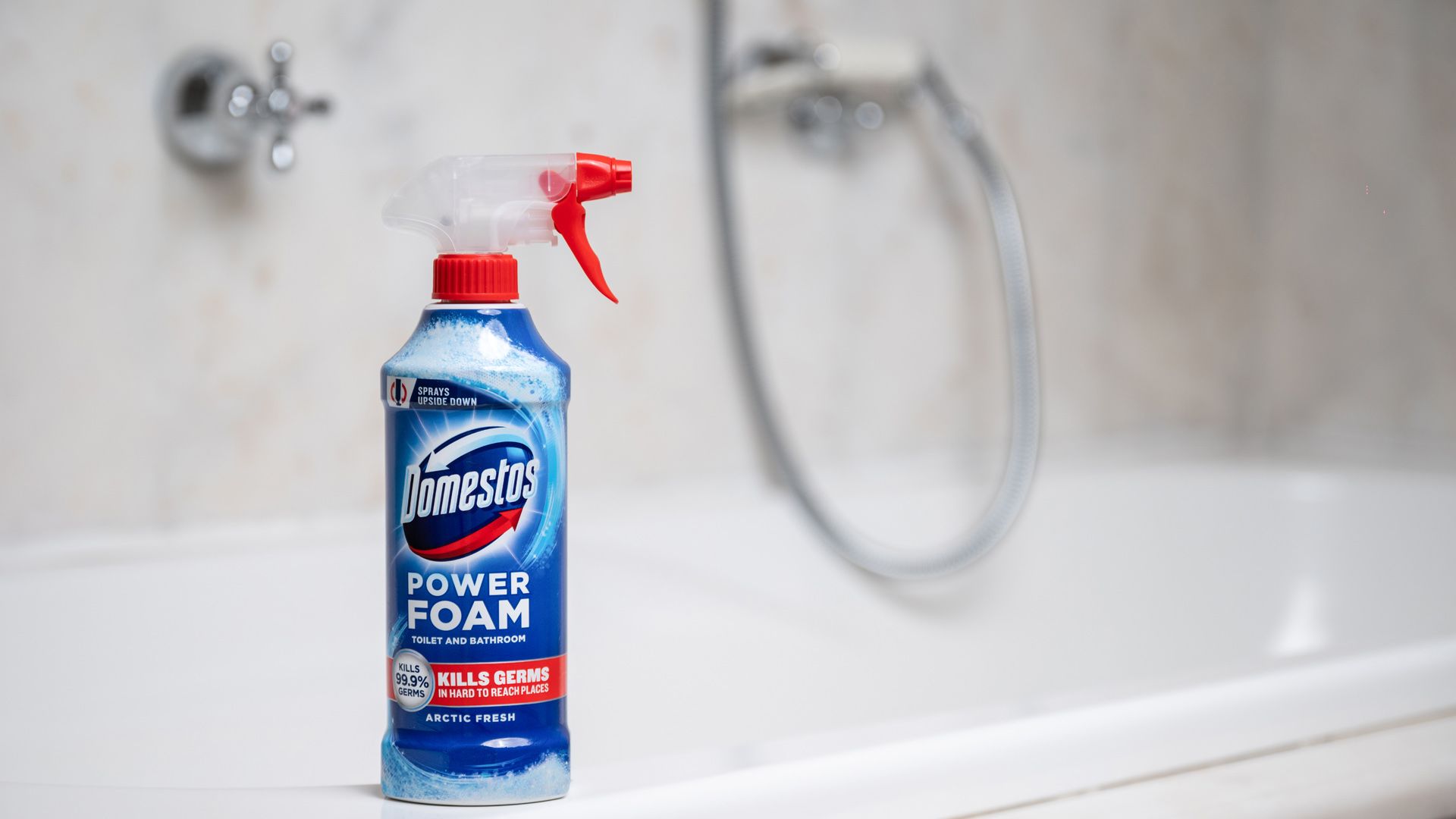The new Domestos Power Foam Spray bottle sits on the edge of a white toilet