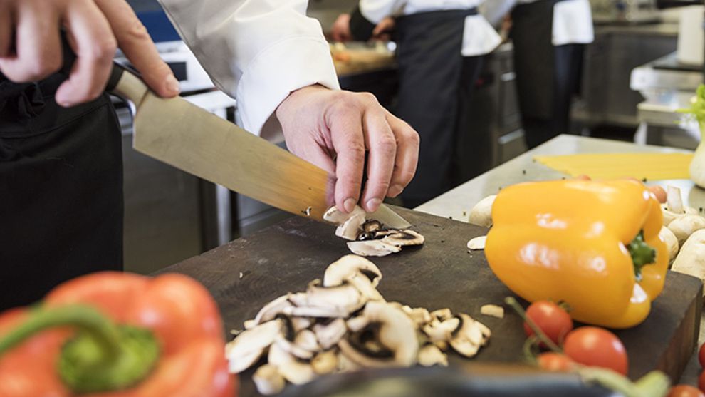 Image of chef in a kitchen cutting up vegetables
