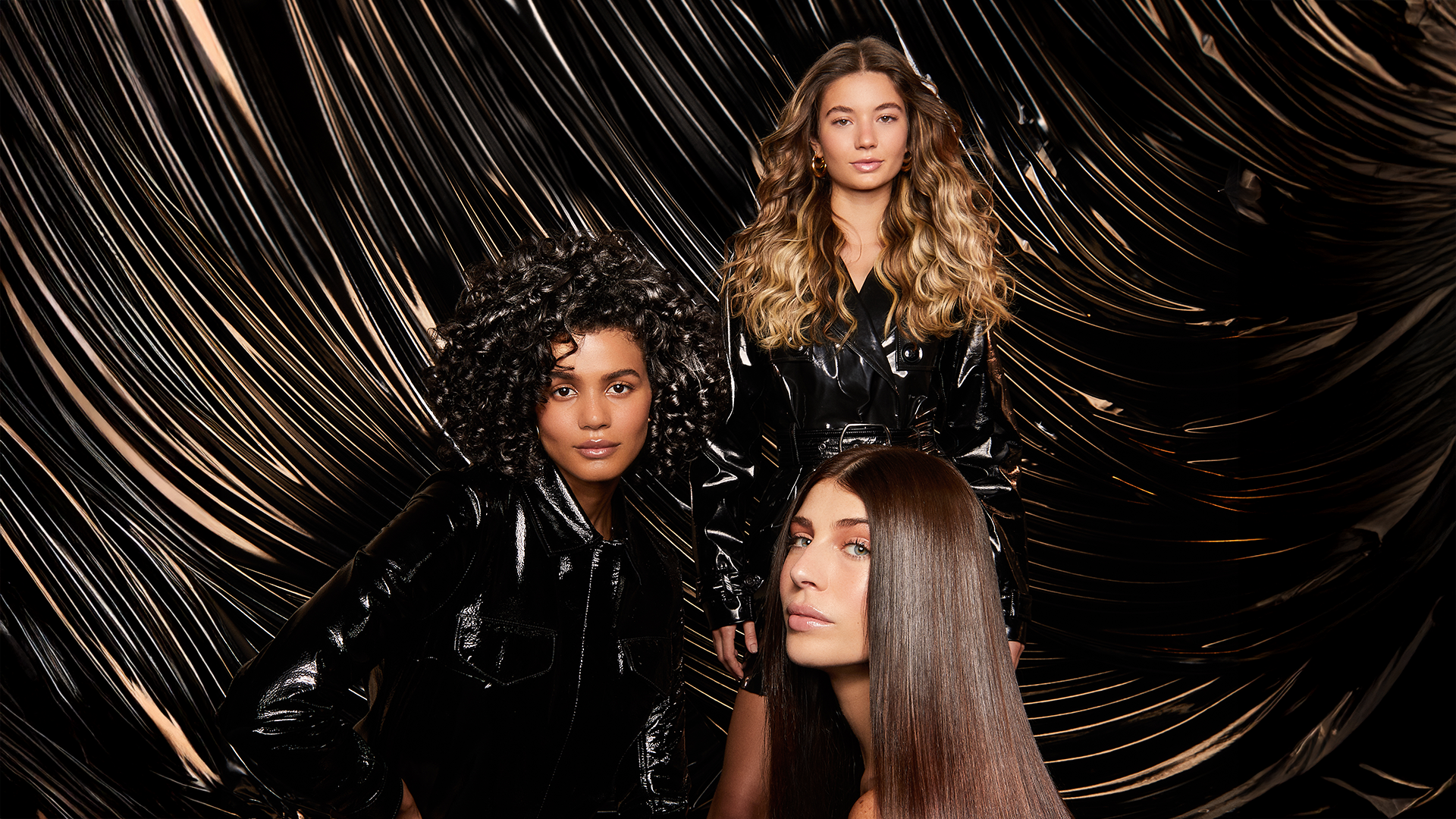 Three Tresemme models pose in front of a brown, silky back drop.