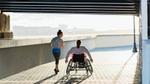 Woman running next to a person in a wheelchair under a bridge